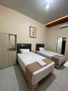 KalasanNawasena Guesthouse Jogja的一间卧室配有两张床和镜子