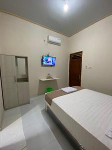 KalasanNawasena Guesthouse Jogja的卧室配有一张床,墙上配有电视。