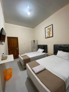 KalasanNawasena Guesthouse Jogja的酒店客房设有两张床和电视。