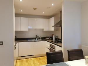 伦敦Homestay Room in Apartment with Stunning Thames River View的厨房配有白色橱柜和黑色家电