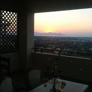 科斯镇Hercules Hills Sea View Villas的配有桌椅的客房享有日落美景。