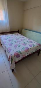 瓜拉派瑞Praia de Setiba - Kitnet的一间卧室配有一张带花卉床罩的床
