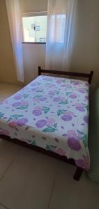 瓜拉派瑞Praia de Setiba - Kitnet的一间卧室配有一张带花卉棉被的床