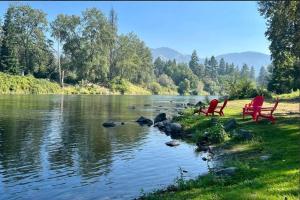 格兰茨帕斯Loft Cabin 2 - Rogue River Resort的两把红椅子坐在河岸边