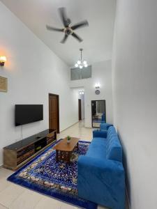 巴西古当three bedroom tarraced house - RainaHomestay Pasir Gudang的客厅配有蓝色的沙发和电视