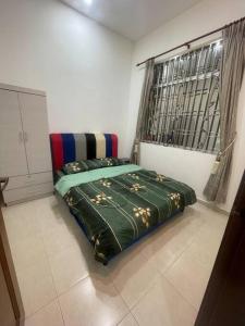 巴西古当three bedroom tarraced house - RainaHomestay Pasir Gudang的一间卧室配有一张带绿色棉被的床和窗户。