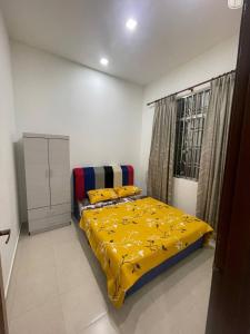 巴西古当three bedroom tarraced house - RainaHomestay Pasir Gudang的一间卧室配有一张黄色毯子床