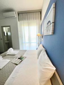 里米尼Hotel Alfa ALL INCLUSIVE 2024的一间卧室配有一张白色大床和蓝色的墙壁