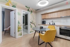 波亚纳布拉索夫Grand Chalet Holiday Apartment Poiana Brasov的厨房配有桌子和2把黄色椅子