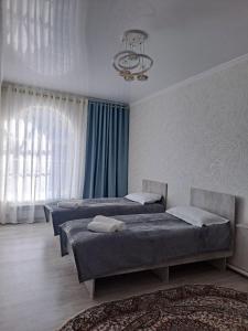卡拉科尔GuestHouse "ERKIN"的一间卧室配有三张床和吊灯。