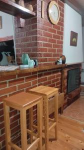 帕莱Vikendica Mašan的厨房配有2张凳子和带时钟的壁炉