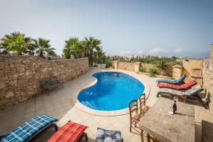 纳杜尔3 Bedroom Farmhouse with Private Pool & Views in Nadur Gozo的庭院内的游泳池,配有桌椅