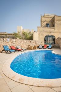 纳杜尔3 Bedroom Farmhouse with Private Pool & Views in Nadur Gozo的一座带椅子的大型游泳池和一座建筑