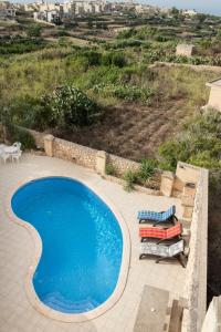 纳杜尔3 Bedroom Farmhouse with Private Pool & Views in Nadur Gozo的一个带躺椅的蓝色游泳池以及一座小山