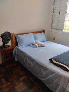佩洛塔斯Apartamento 2 quartos的一间卧室配有一张带蓝色枕头的床和风扇