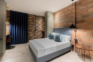 麦德林Apartahotel Medellin的卧室配有白色的床和砖墙