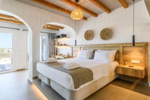 Merchia BeachMykonos Residence Villas & Suites Merchia Beach的一间卧室配有一张带白色床单的大床