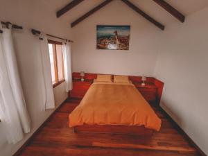Isla de SolEcolodge Santo Campo的一间卧室配有一张带橙色毯子的床