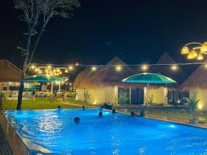 贡布SEA SAND RESORT的夜间带遮阳伞的游泳池