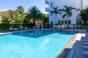 劳德代尔堡Beachside Bliss 1BR Oasis + Pool in Ft Lauderdale的一座棕榈树大型游泳池和一座建筑