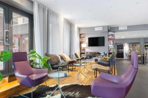 斯德哥尔摩Aiden by Best Western Stockholm Kista的客厅配有紫色椅子和平面电视