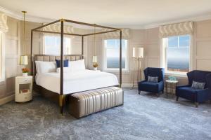 半月湾半月湾丽思卡尔顿酒店的一间卧室配有一张床和两张蓝色椅子