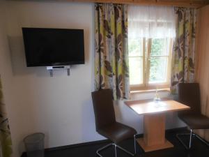 上柯尼希山麓米尔巴赫巴奇古特农家酒店的一间房间,墙上有桌子和电视
