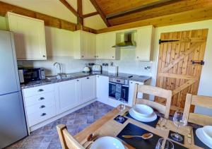 LlandinamCorlan的厨房配有白色橱柜和桌椅