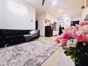 新山New! 4-7pax 2bedrooms condo near Mount Austin JB的客厅配有黑色沙发和粉红色的鲜花