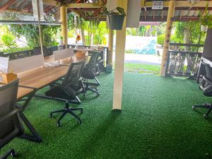 拉迈Amy Village Garden Resort的绿色地毯上带桌椅的办公室