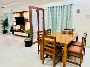 蒂鲁帕蒂TrueLife Homestays - Sai Nivas - 3BHK AC Apartments for group of families - Best location - Flyover to Alipiri gate - Walk to PS4 Veg Restaurant - Modular Kitchen - Super fast WiFi - Android TV - 250 Jio Channels - Easy access to visit all Temples的一间带木桌和椅子的用餐室