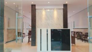 库塔Mahestu Hotel的配有桌椅和玻璃墙的房间