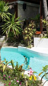 爱妮岛Happiness Boutique Resort的花园中的一个游泳池,种植了植物和鲜花