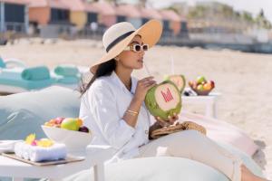 马斯喀特马斯喀特千禧国际酒店的坐在海滩上喝瓜子酒的女人