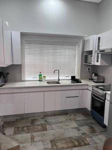 GqeberhaBeverley Grove Guest House的厨房配有白色橱柜、水槽和窗户。
