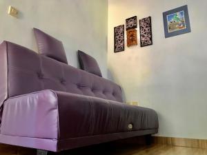 姆杜克Umah De Madya & Rooftop De Madya的墙上挂着照片的房间的紫色沙发
