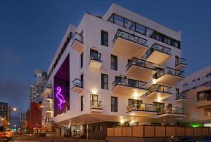 特拉维夫Brown Beach House Tel-Aviv, a member of Brown Hotels的白色的建筑,上面有紫色的标志