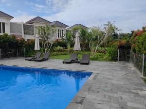北干巴鲁Sweet City Villa near Mall Pekanbaru Sudirman的房屋旁的游泳池配有椅子和遮阳伞