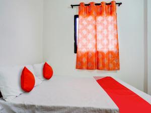 那格浦尔OYO Flagship RJ Hotel的一间卧室配有一张带红色枕头的床和一扇窗户