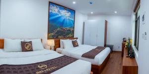 老街市Big Hotel Lào Cai的酒店客房设有两张床,墙上挂有绘画作品