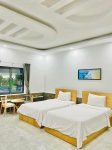 Xóm Phước MỹKhách sạn Khang Điền 2的一间卧室配有两张床和一张桌子及一张桌子。