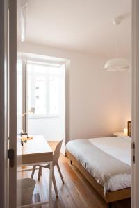 里斯本Amaro II - Sleek 2 bedroom apartment in Alcantara的一间卧室配有一张床、一张书桌和一个窗户。