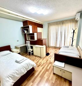 地拉那Rolling Apartment Tirana - Near Blloku的一间卧室配有两张床、一张桌子和一把椅子