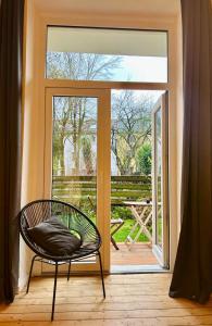 波鸿FeelsLikeHome - Stylische und zentrale Altbauwohnung mit Terrasse&Garten的滑动玻璃门前的椅子