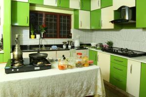 科钦茉莉别墅民宿的厨房配有绿色橱柜和一张带食物的桌子。