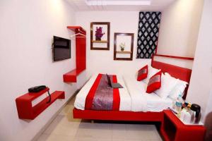 新德里OYO Flagship Hotel BalaG的一间卧室设有红色和白色的床和一台电视。