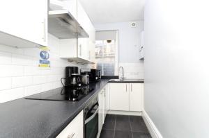 伦敦Oxford Circus Central Apartments的厨房配有白色橱柜和黑色台面
