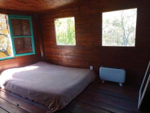 蒂格雷Cabaña los sauces的小木屋内的卧室,设有2扇窗户