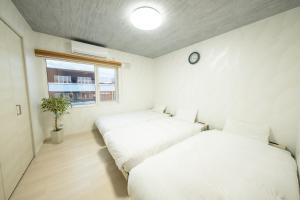 富良野furano ski rabi的墙上挂钟的房间里设有两张床
