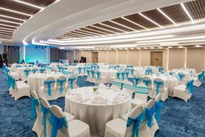 岘港Melia Danang Beach Resort的一个带白色桌子和蓝色椅子的大型宴会厅